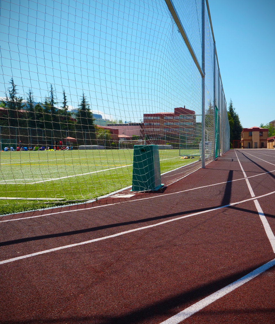 Imagen de una de las curvas de la pista de atletismo de la Facultad de Ciencias del Deporte. A su lado se sitúan las gradas y el campo de fútbol