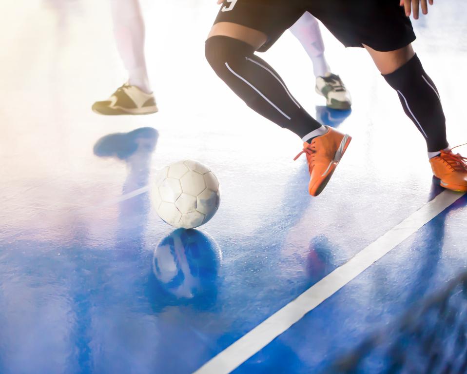 Fútbol Sala piernas jugador controlando un balón y evitando que salga por fuera de banda
