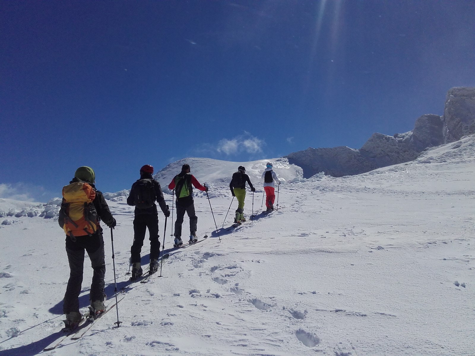 Un grupo de personas practica esquí de montaña en una cima nevada